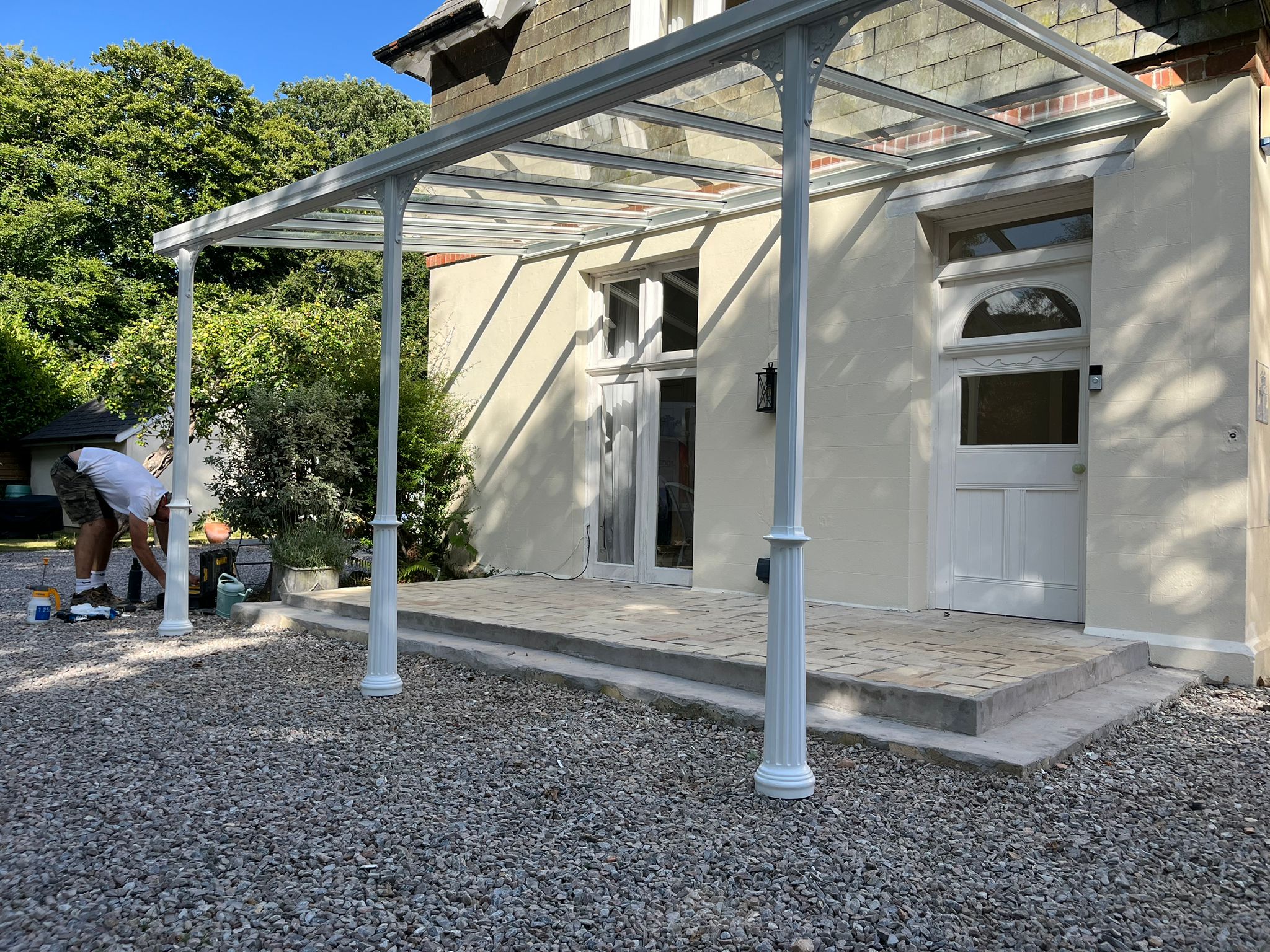 Glass Veranda roof on a Victorian house in Plymouth, Devon and powder coated in traffic white with ornate Victorian posts and gallows brackets by All Weather Canopies South West Ltd