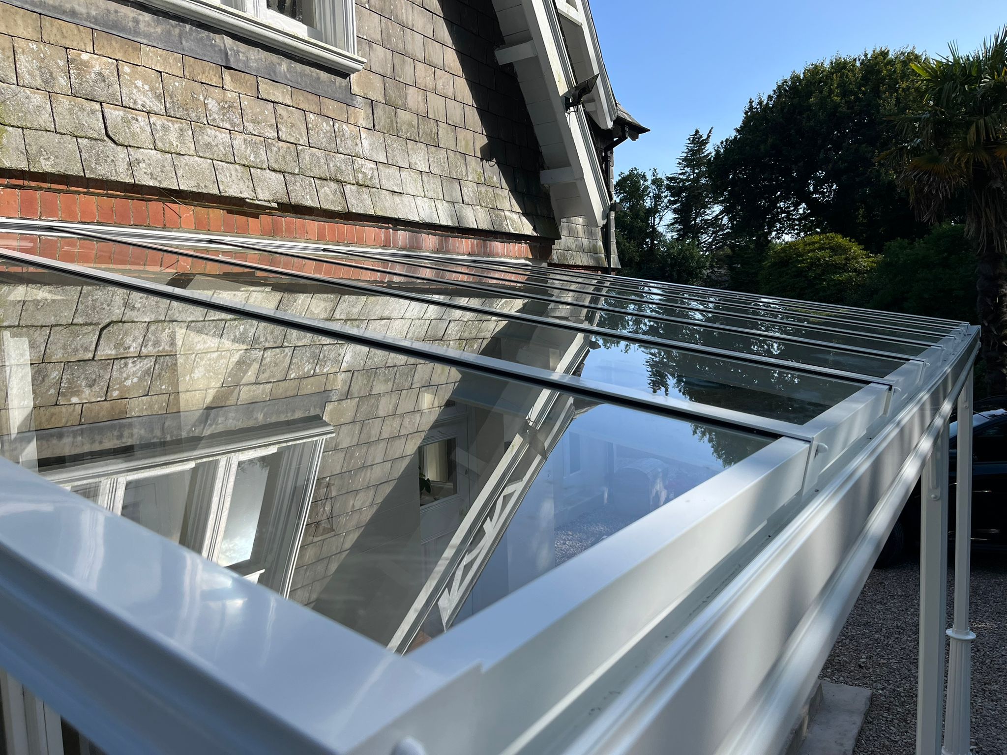 Glass Veranda roof on a Victorian house in Plymouth, Devon and powder coated in traffic white with ornate Victorian posts and gallows brackets by All Weather Canopies South West Ltd