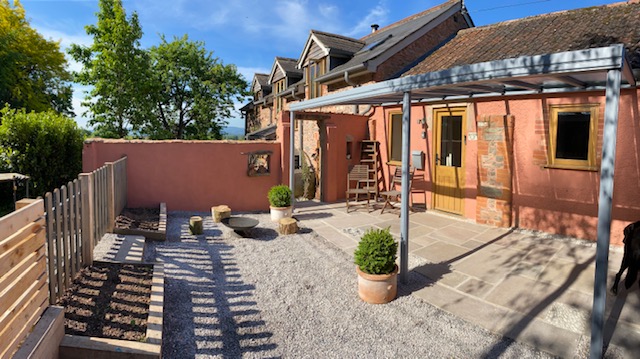Outdoor patio area featuring a canopy structure, gravel surface, and potted plants.