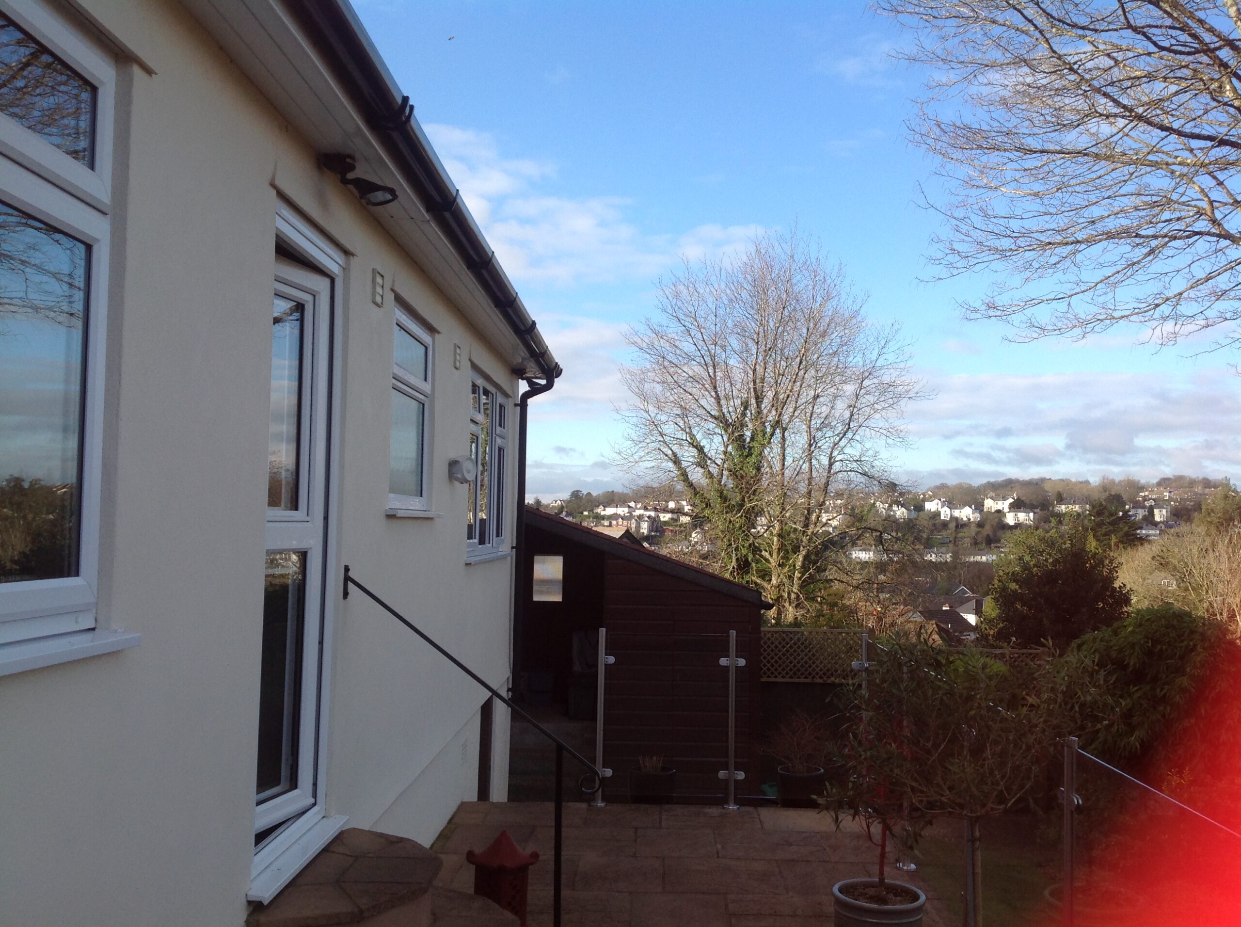 Exterior view of a residential building with windows and a garden area in the foreground.