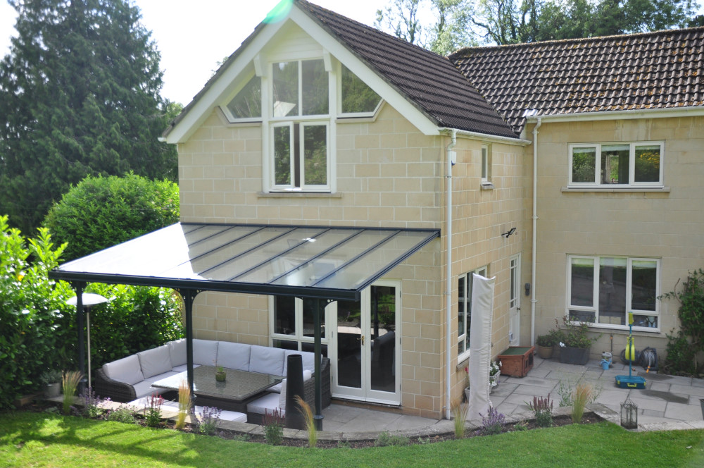 Victorian-style veranda canopy with a glass roof in anthracite grey, attached to a house.
