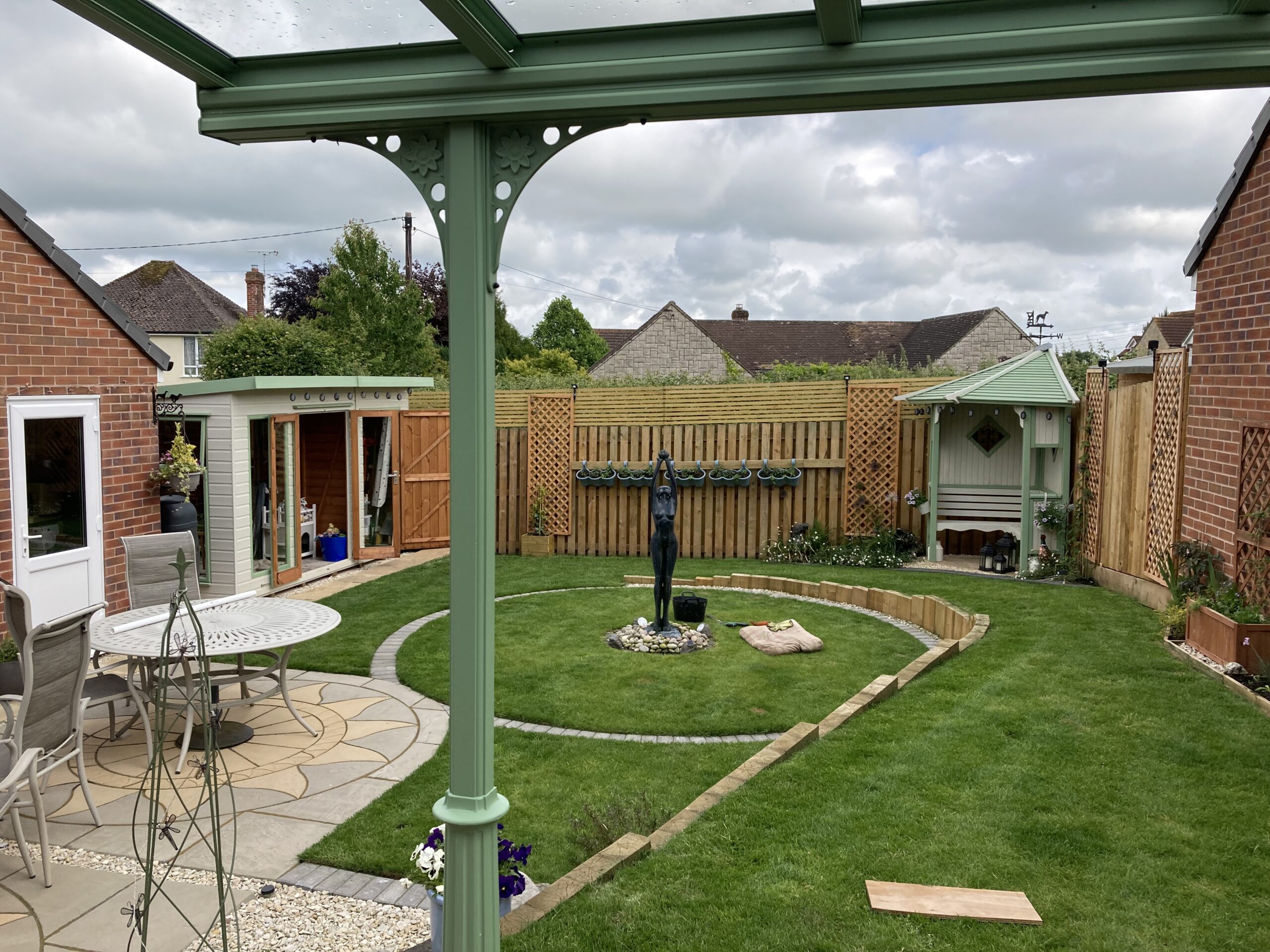 Pale green veranda canopy with a glass roof, designed in a traditional Victorian style.