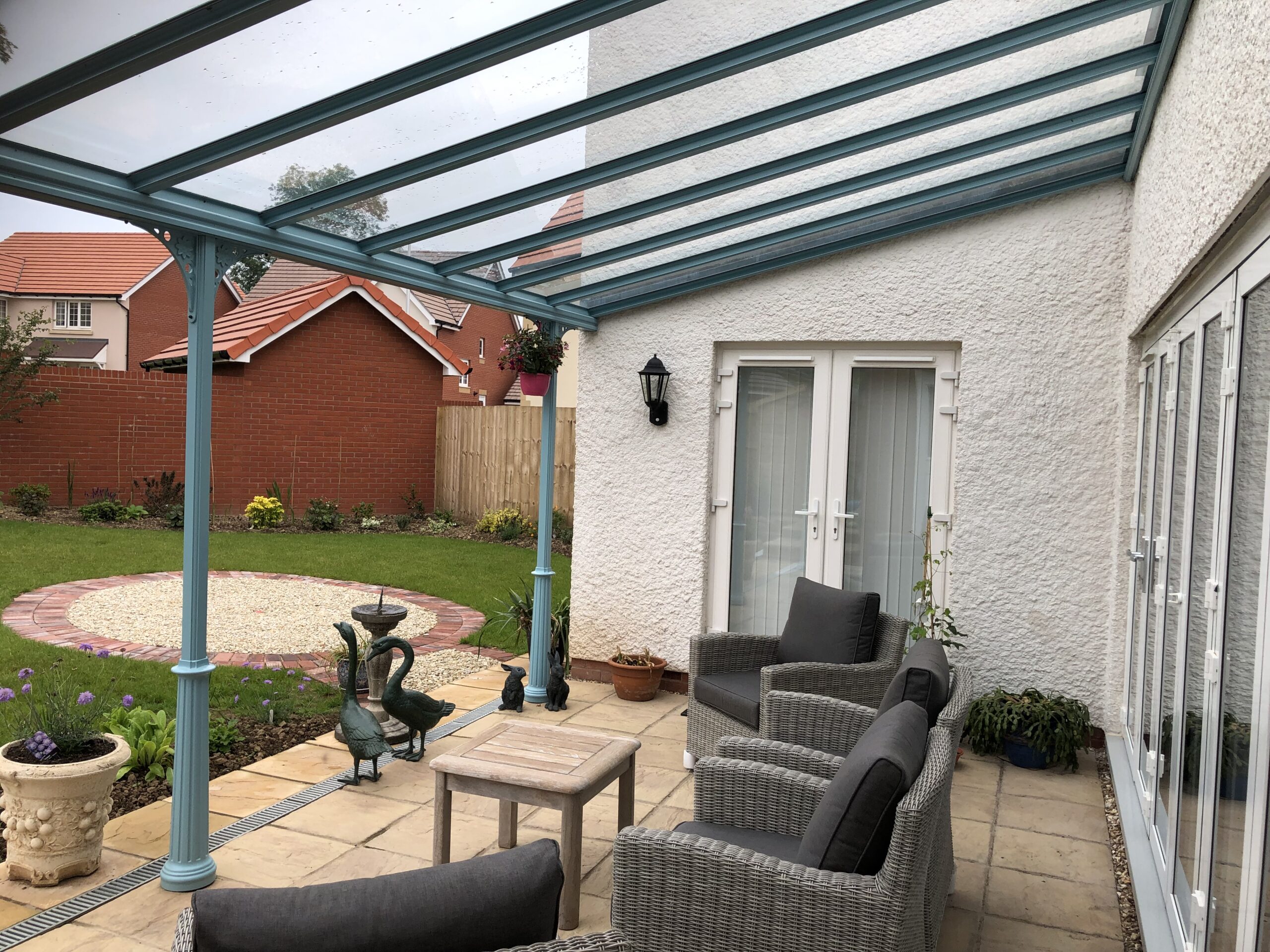 Veranda canopy with a glass roof in pastel turquoise, supported by blue columns.