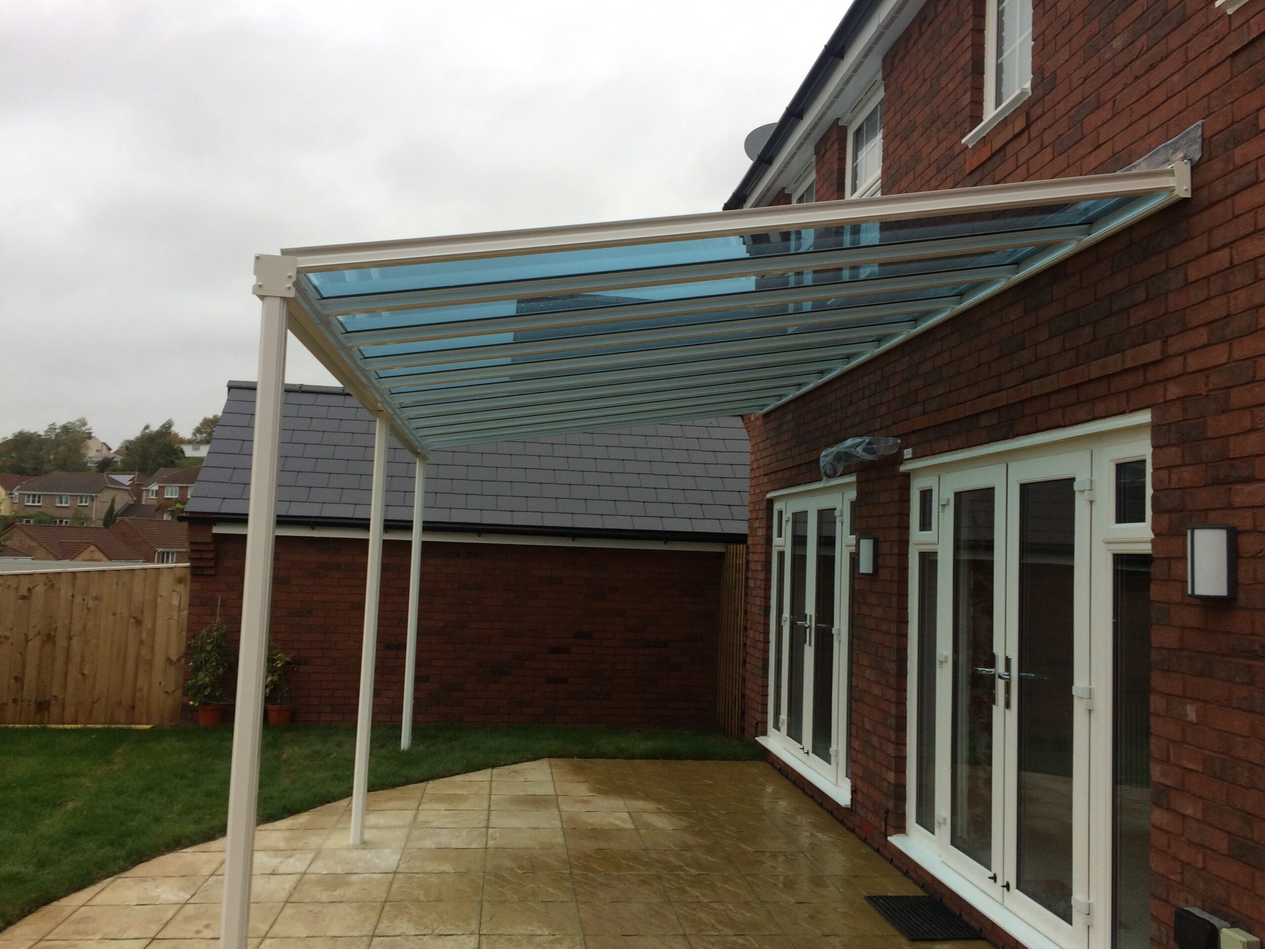 White veranda canopy with a glass roof attached to a brick house exterior.